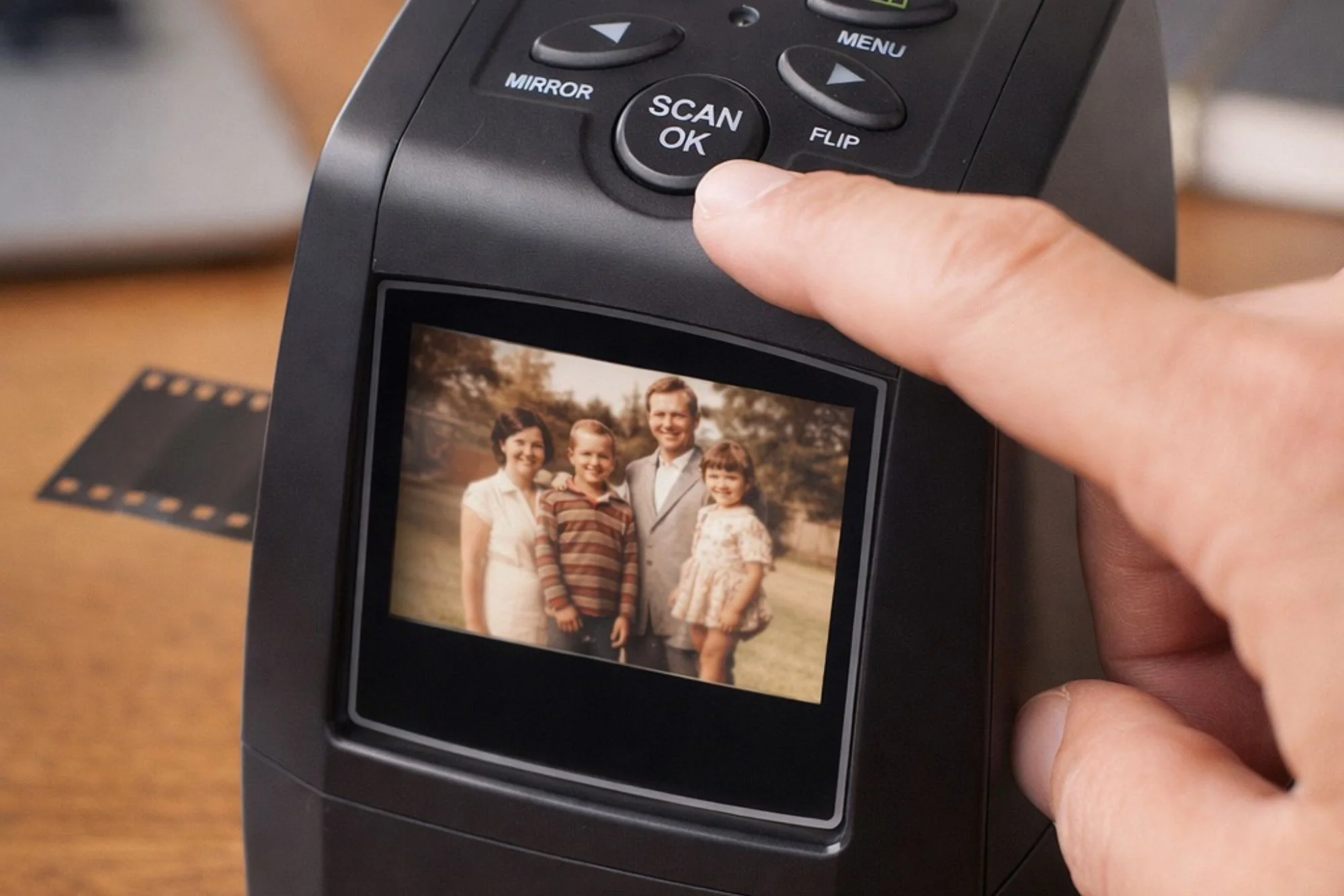 A finger pressing the scan button on the MemoryVault film scanner